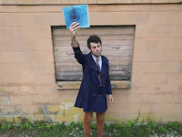 a man in a blue coat holding up a blue piece of paper